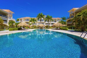 Ein Swimmingpool mit Liegestühlen und Palmen, umgeben von Hotelgebäuden.