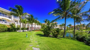 A well-maintained lawn with a stone pathway leading to a building with balconies. - Iberostate 2-Bedroom Condo - Terrace, BBQ, Beach Access, Lake & Golf Views (Punta Cana)