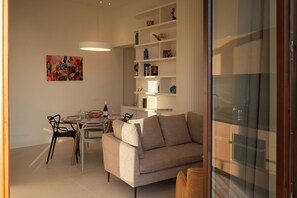 Ein modernes Wohnzimmer mit einer Couch, einem Esstisch, Stühlen und einem Bücherregal.