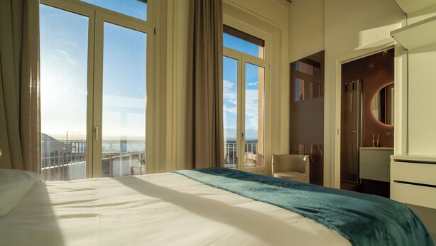 A hotel room with a large bed, a view of the city, and a bathroom with a modern design. - Residenza 2 Venti-Intera by Ortigia Apartments (Syracuse)