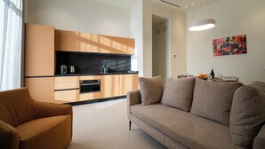 A modern living room with a sofa, a coffee table, and a kitchen area with cabinets and a countertop. - Residenza 2 Venti-Intera by Ortigia Apartments (Syracuse)