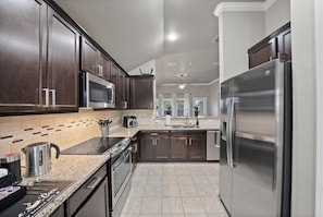 A modern kitchen with dark wood cabinets, stainless steel appliances, and a tiled backsplash.