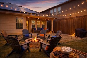 Un jardin avec un foyer, un espace salon extérieur et un barbecue.