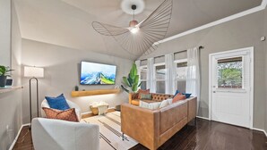 Ein modernes Wohnzimmer mit einer Couch, einem Fernseher, einer Lampe und einem Deckenventilator.