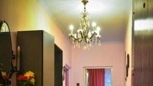 Un couloir orné d’un lustre, doté de meubles en bois et d’une porte donnant sur une autre pièce.