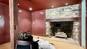 Ein Zimmer mit Kamin aus Stein, Holzwänden und rustikalem Dekor.