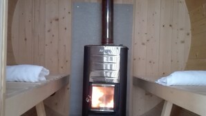 A wood-burning stove in a cabin with two beds and a rug on the floor. - Holiday Home Plattenstein with Private Terrace, Garden, Sauna, Wi-Fi and BBQ (Kirchberg im Wald)