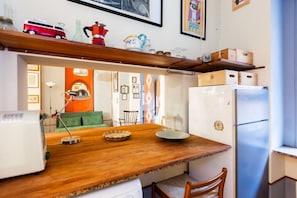 Eine kleine Küche mit einer Holz Arbeitsplatte, einem weißen Kühlschrank und einem Essbereich mit einem grünen Sofa und Stühlen.