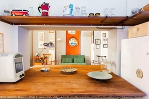 Eine Küche mit einem Holztisch, einem Retro-Toaster, einem grünen Sofa und einer Wand mit gerahmten Bildern.
