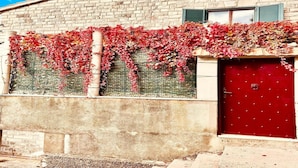 A building with a brick facade, a red door, and a vine-covered wall. - Spacious Stone Villa with Sea Views (Dubrovnik)