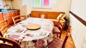 A dining area with a round table covered by a patchwork tablecloth, surrounded by wooden chairs. - Spacious Stone Villa with Sea Views (Dubrovnik)