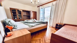 A bedroom with a bed, wooden wardrobe, bedside table, and a view of the outdoors. - Spacious Stone Villa with Sea Views (Dubrovnik)