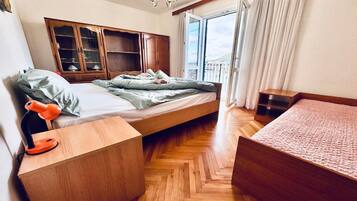 A bedroom with a bed, wooden wardrobe, bedside table, and a view of the outdoors.