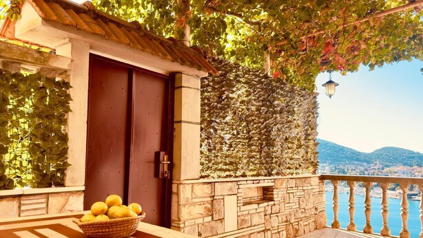 A balcony with a stone wall, a door, and a basket of lemons. - Spacious Stone Villa with Sea Views (Dubrovnik)