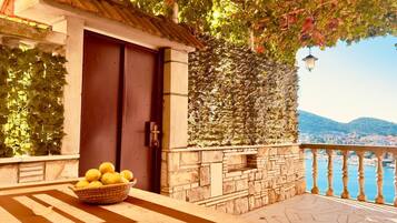 A balcony with a stone wall, a door, and a basket of lemons.