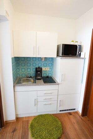 Une cuisine compacte équipée d’un four à micro-ondes, d’une machine à café et d’un évier.