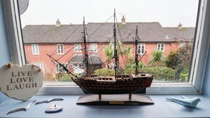 A model ship on a windowsill with a 'Live Love Laugh' sign, a bird figurine, and a small dish. - Lilly Cottage (Woodbridge)