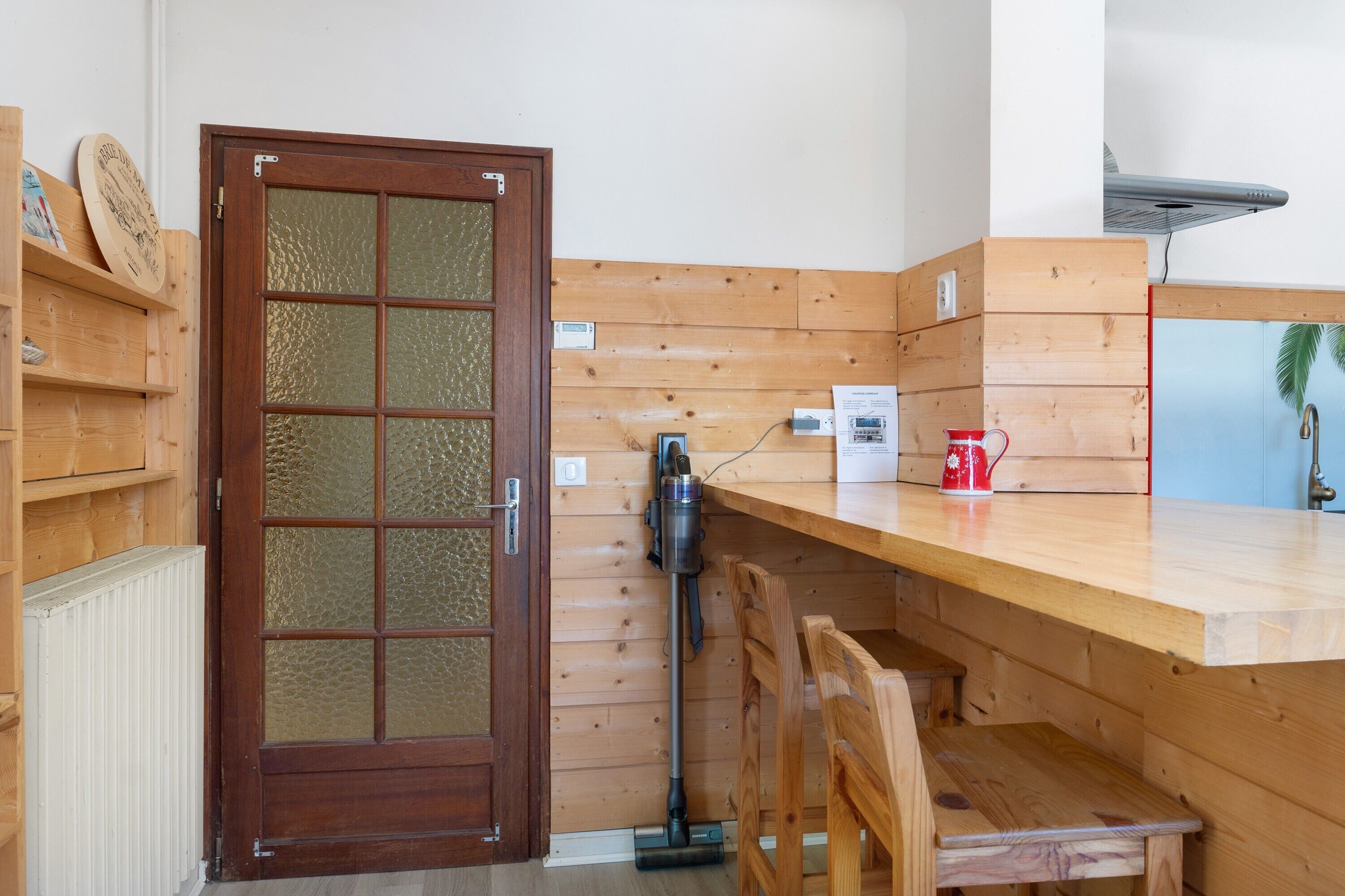 Un interior de madera con una puerta, un banco, una mesa y un radiador.