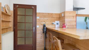 Un interior de madera con una puerta, un banco, una mesa y un radiador.