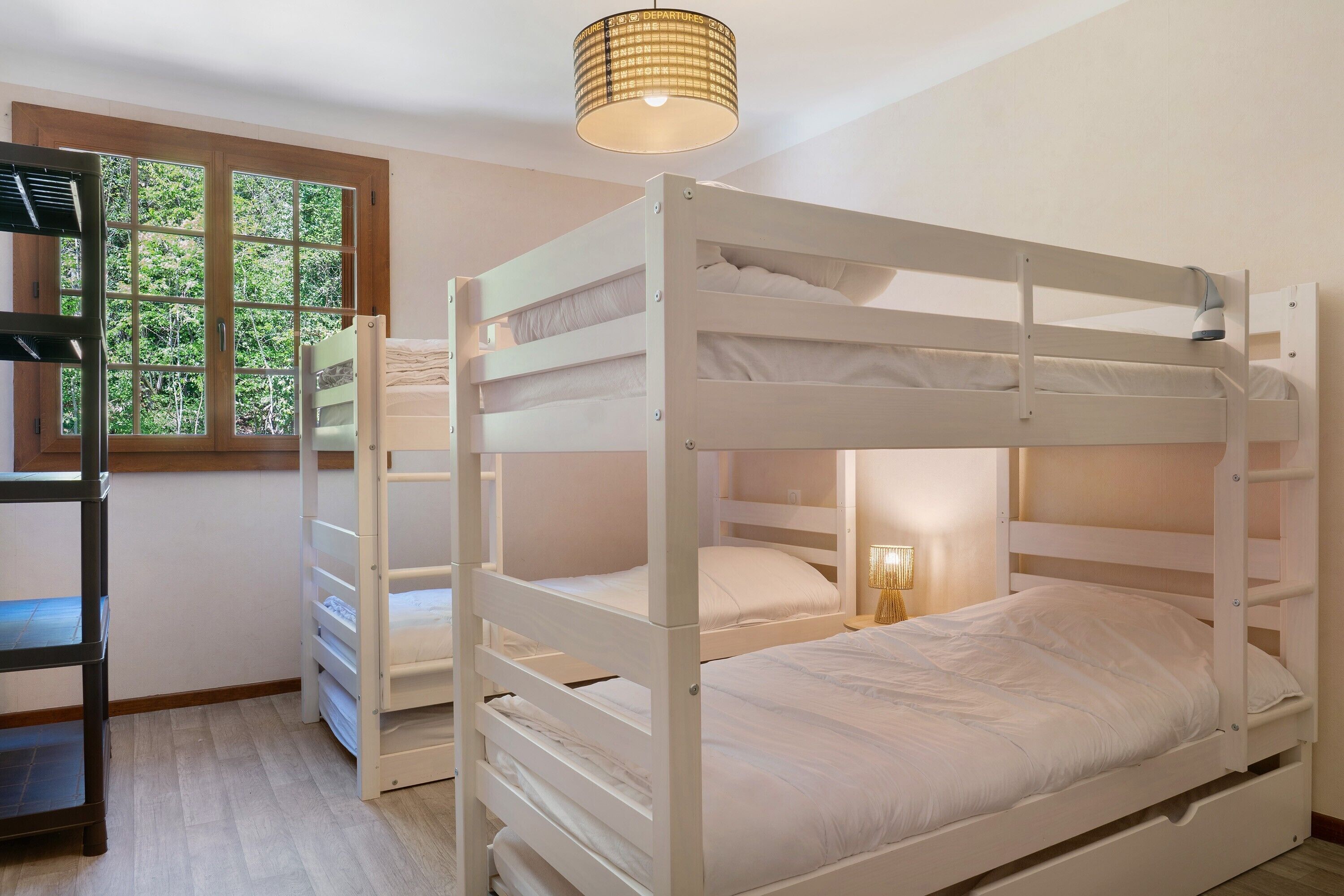 A bunk bed room with a window, a lamp, and a shelf.