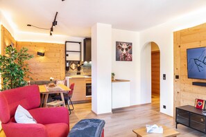 Un espacio habitable moderno con comedor, cocina y televisor montado en la pared.