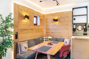 A cozy room with wooden walls, a dining table with a red and white checkered table runner, and a gray sofa with a reindeer pillow.