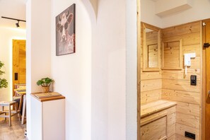 A wooden interior with a wooden door, a small table with a plant, and a framed picture on the wall. - Ammerstube – Alpine Design Holiday Apartment in Central Oberammergau (Oberammergau)