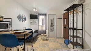 Ein kompakter Wohnbereich mit Essplatz, einer Couch, einem kleinen Tisch und einem Kleiderschrank mit Aufhängefläche.