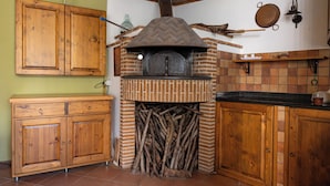 A kitchen with a wood-burning oven, wooden cabinets, and a brick wall. - Il giardino dei Gigli, few steps from the sea (Meta)