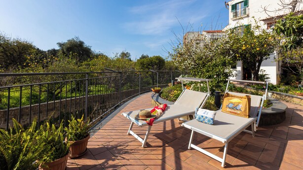 A terrace with two lounge chairs, a small table, and potted plants. - Il giardino dei Gigli, few steps from the sea (Meta)