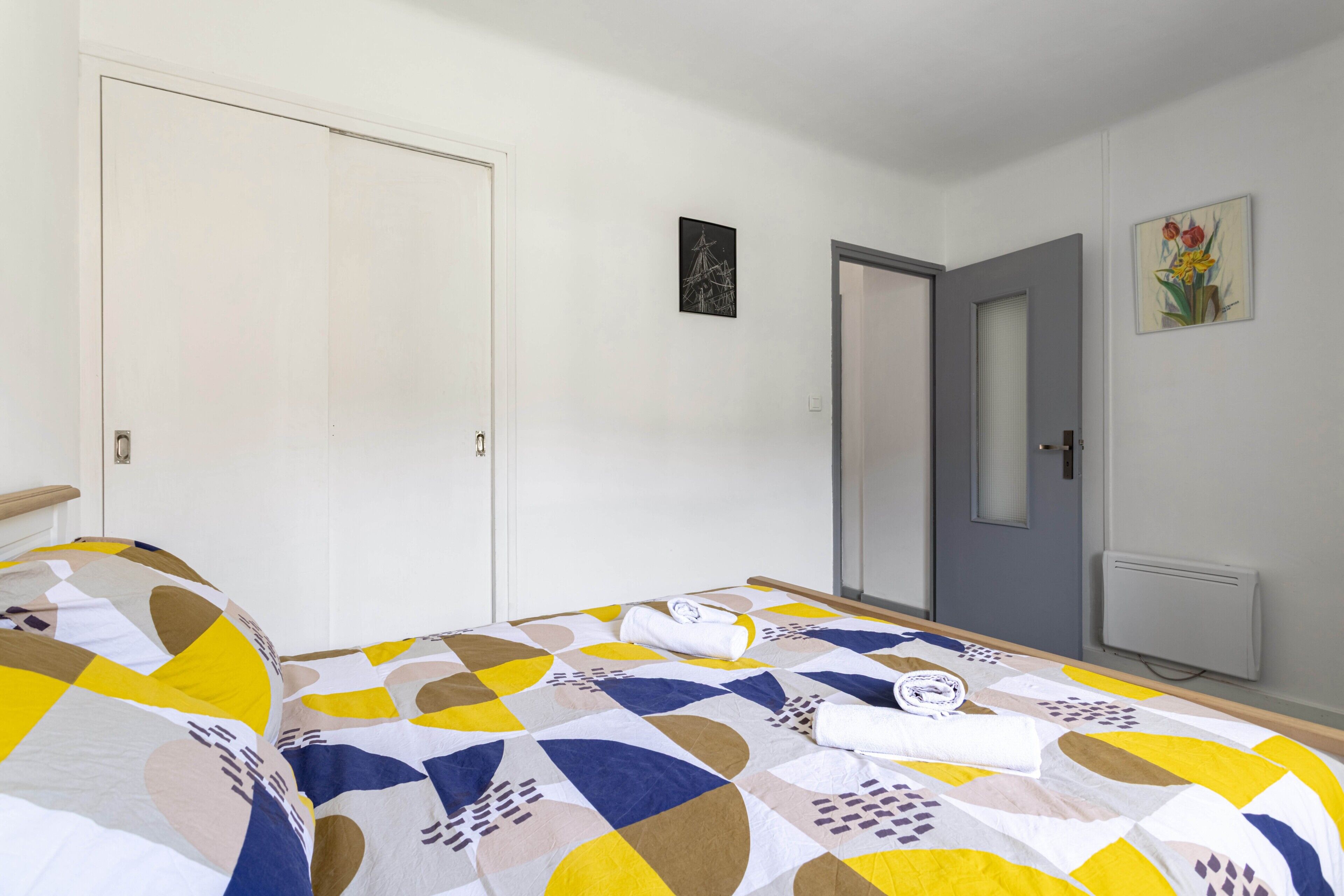 Une chambre à coucher avec un lit, une porte et un tableau accroché au mur.