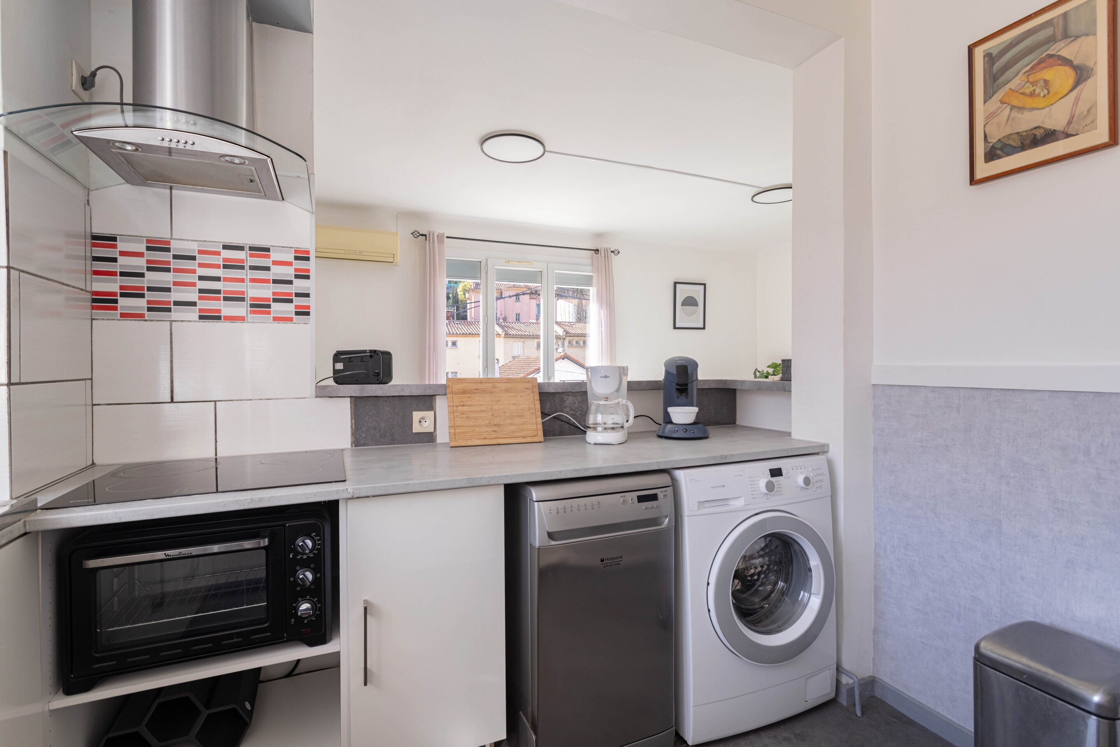 A compact kitchen with a built-in toaster oven, a dishwasher, and a washing machine.
