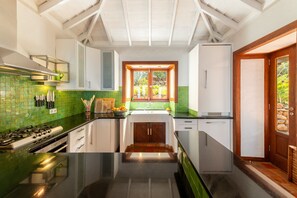 A kitchen with a gas stove, white cabinets, a green tiled backsplash, and a wooden door.