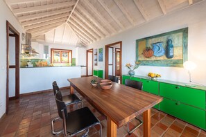 A dining area with a wooden table, chairs, and a green kitchen counter.