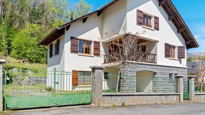 A two-story house with a balcony, stone foundation, and a green gate. - Apartment 'L'arrieulat 2' with Mountain View, Shared Terrace and Shared Garden (Argelès-Gazost)