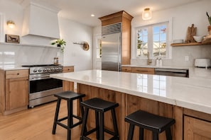 A modern kitchen with a large island, stainless steel appliances, and wooden accents.