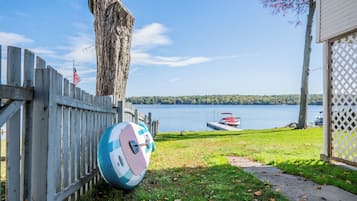 Une clôture en bois, un ballon de volley-ball, un quai avec un bateau et une vue sur le lac.