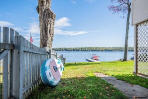 Una valla de madera, un voleibol, un muelle con un bote y vista al lago.