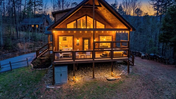 Una cabaña de madera con terraza, varios ventanales y cimientos de piedra.