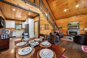 Ein Holzblockbau-Innenraum mit Essbereich, Küche, Wohnzimmer, Kamin und einer Treppe.