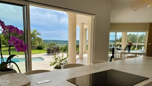 Eine moderne Küche mit einem großen Fenster, einem eingebauten Herd und Blick auf Pool und Garten.
