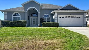 A two-story house with a garage, a front entrance with a semi-circular arch, and a well-maintained lawn. - Star Villa: Private Pool with 24/7 Support! (Davenport)