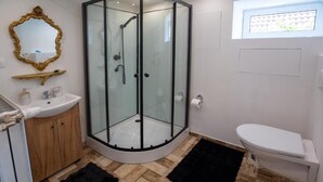 Un baño moderno con ducha de vidrio, lavamanos blanco y un inodoro.