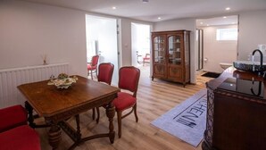 Un comedor con una mesa de madera, sillas rojas y un aparador con puertas de vidrio.