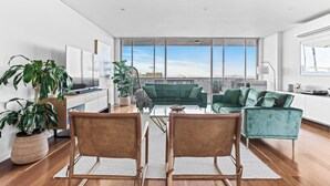 A spacious living room with a large window, a green sofa, a coffee table, and two chairs. - City Perch Escape Sweeping Penthouse style Haven (Wollongong)