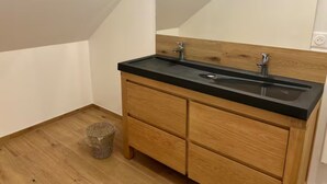 A small bathroom with a wooden vanity, black countertop, and a single sink. - Gîte La Garenne (La Ferté-Saint-Aubin)