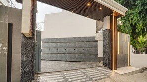 Ingresso di un edificio moderno con facciata in pietra, cancello in metallo e portico coperto.