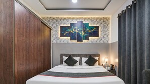 Una moderna camera d'hotel con un letto grande, un'opera d'arte appesa al muro e un comodino con una lampada.