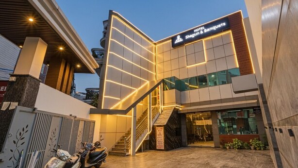 Ingresso moderno di un hotel con una scalinata che conduce alla hall, una insegna con il nome dell'hotel e uno scooter parcheggiato all'esterno.