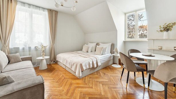 Ein modernes Schlafzimmer mit Bett, Sofa, Esstisch und einer Chandelier.